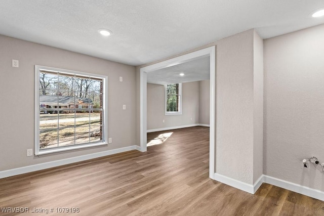 unfurnished room with recessed lighting, a textured ceiling, baseboards, and wood finished floors