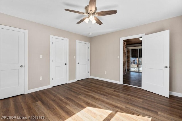 unfurnished bedroom with two closets, ceiling fan, baseboards, and dark wood-type flooring