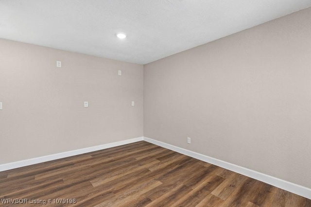 spare room featuring baseboards, dark wood-type flooring, and recessed lighting