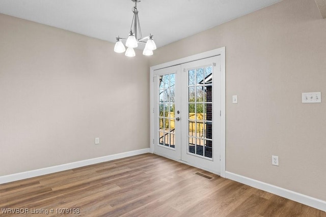 interior space with french doors, visible vents, an inviting chandelier, wood finished floors, and baseboards