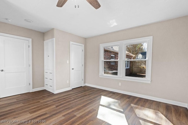 unfurnished bedroom featuring a ceiling fan, dark wood-style flooring, visible vents, and baseboards