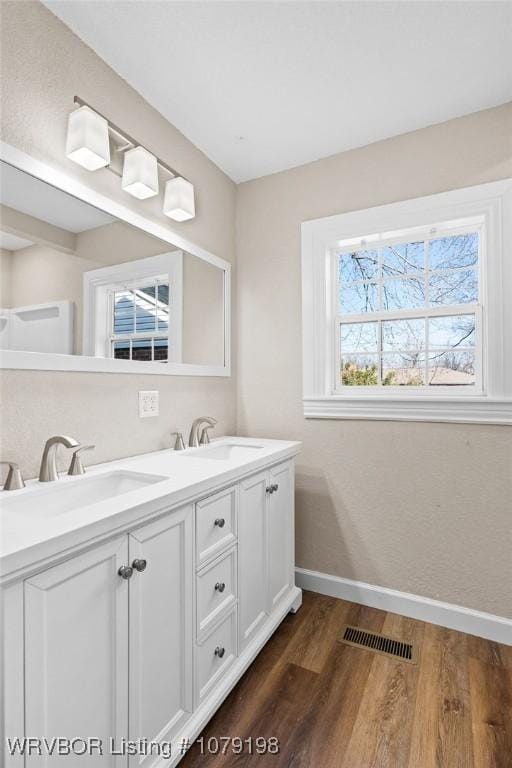 full bath with wood finished floors, a sink, visible vents, and baseboards