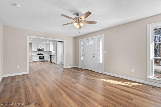 foyer featuring a ceiling fan, baseboards, visible vents, and wood finished floors