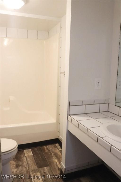 full bathroom featuring vanity, hardwood / wood-style floors, toilet, and washtub / shower combination