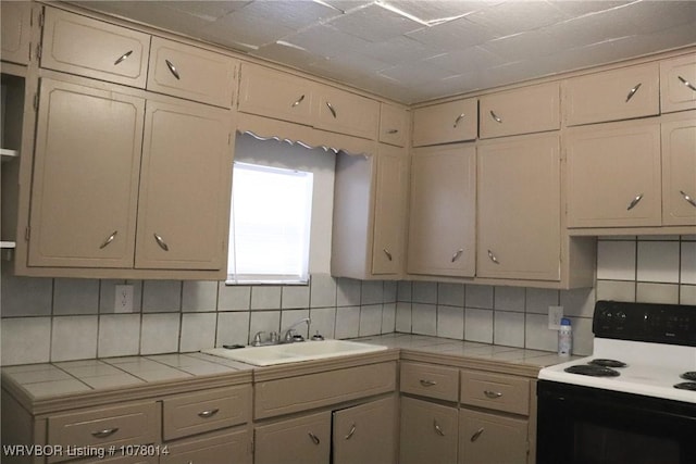 kitchen with sink, tile countertops, decorative backsplash, and electric stove