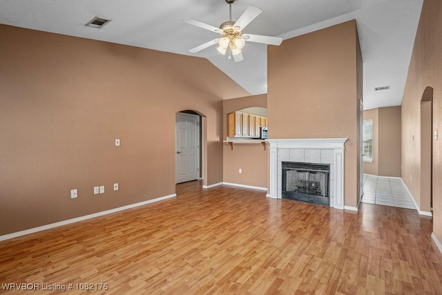3707 Princeton Ct, Van Buren, AR 72956 - unfurnished living room with arched walkways, light wood-style floors, ceiling fan, a tiled fireplace, and vaulted ceiling