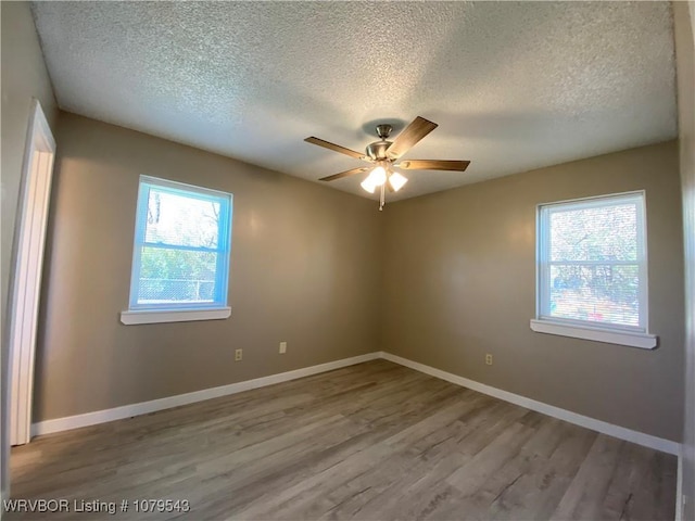 empty room featuring baseboards, a healthy amount of sunlight, and wood finished floors