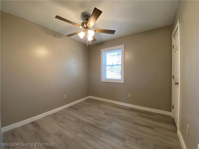 unfurnished room with ceiling fan, baseboards, a textured ceiling, and wood finished floors