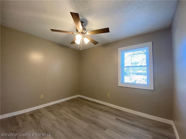 spare room featuring a ceiling fan, wood finished floors, baseboards, and a textured ceiling