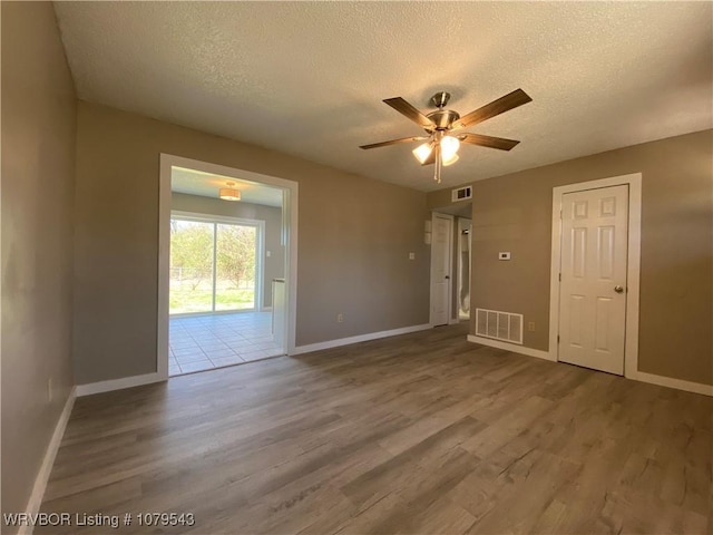 empty room with wood finished floors, visible vents, and a textured ceiling