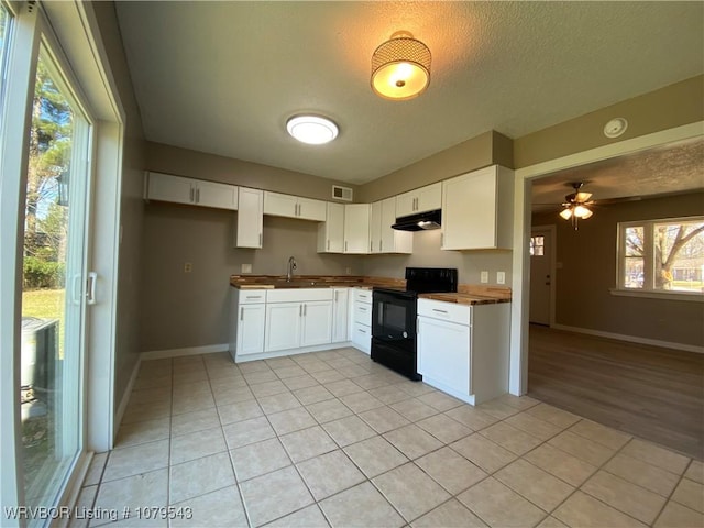 kitchen featuring light tile patterned floors, visible vents, black electric range, under cabinet range hood, and a textured ceiling