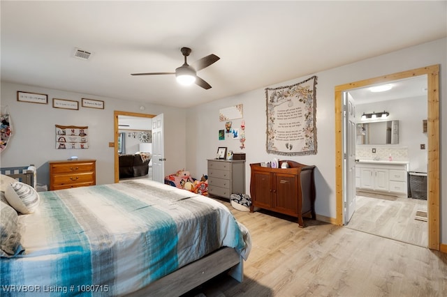 bedroom featuring light wood-style floors, a ceiling fan, ensuite bathroom, and visible vents