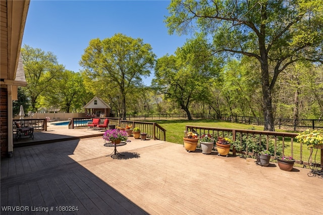 view of patio / terrace featuring a fenced in pool, a deck, a fenced backyard, and an outbuilding