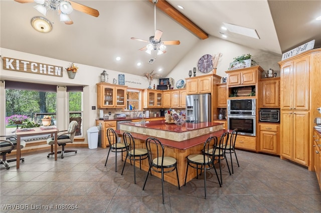 kitchen with stainless steel appliances, a kitchen island, beam ceiling, and ceiling fan