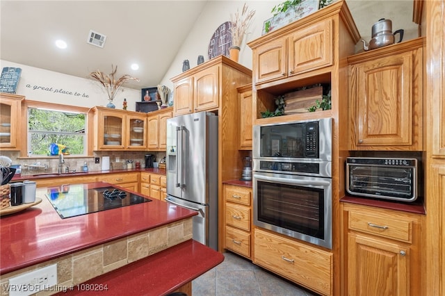 kitchen with visible vents, lofted ceiling, stainless steel appliances, decorative backsplash, and a sink
