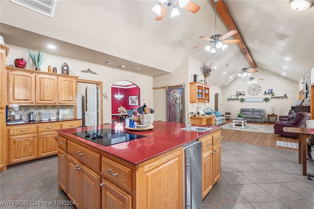 kitchen with arched walkways, a ceiling fan, a sink, vaulted ceiling with beams, and black electric cooktop
