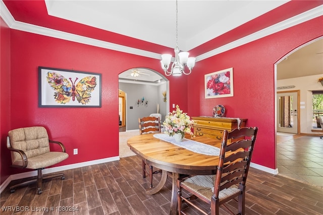 dining space featuring crown molding, a tray ceiling, arched walkways, and wood tiled floor