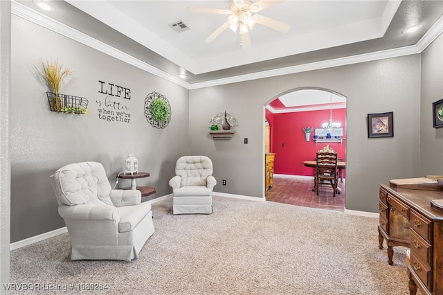sitting room with a tray ceiling, carpet flooring, ceiling fan, and visible vents