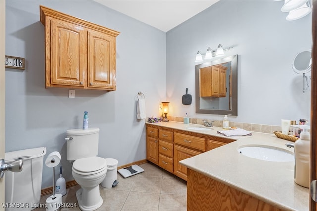 bathroom featuring toilet, tile patterned floors, vanity, and baseboards