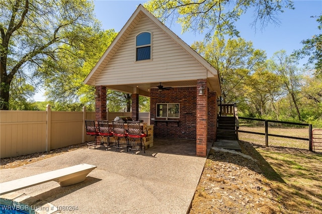 view of patio / terrace with a ceiling fan, fence private yard, and stairs