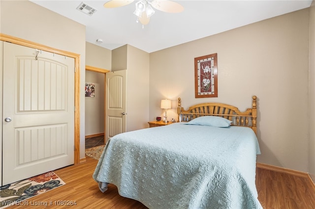 bedroom with wood finished floors, ceiling fan, baseboards, and visible vents