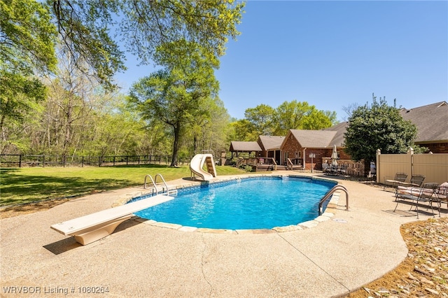 view of pool featuring a yard, a water slide, a patio area, fence, and a fenced in pool