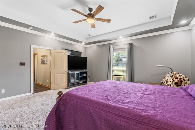 bedroom with a tray ceiling, crown molding, visible vents, and carpet