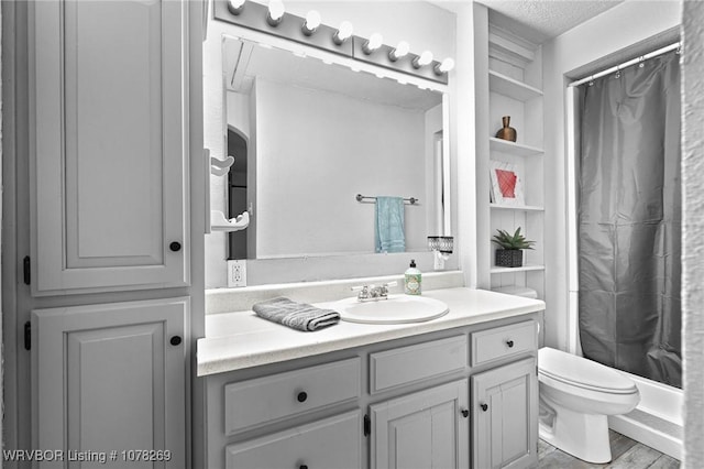 bathroom featuring walk in shower, toilet, a textured ceiling, vanity, and built in features