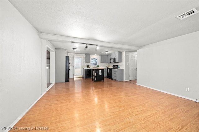 unfurnished living room featuring a textured ceiling and light wood-type flooring