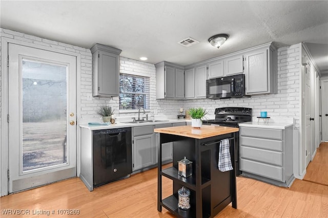 kitchen with gray cabinetry, a center island, sink, and black appliances