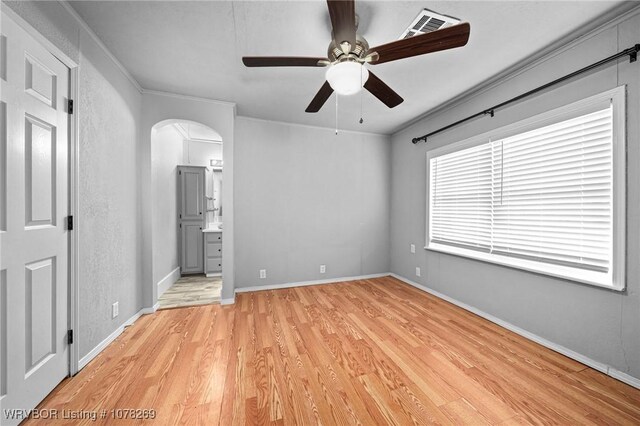 unfurnished bedroom featuring ceiling fan, ornamental molding, ensuite bath, and light hardwood / wood-style flooring