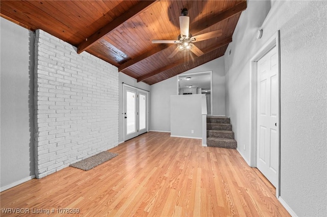 unfurnished living room featuring ceiling fan, lofted ceiling with beams, brick wall, wooden ceiling, and light wood-type flooring