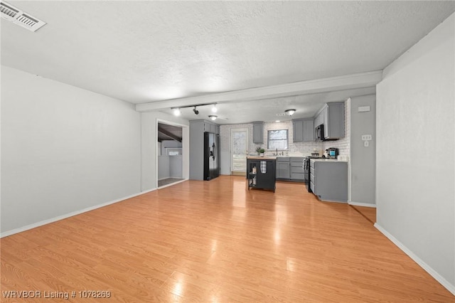 unfurnished living room featuring a textured ceiling and light hardwood / wood-style flooring