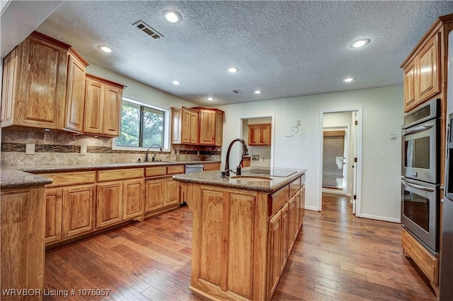 kitchen with hardwood / wood-style flooring, sink, an island with sink, and stainless steel appliances