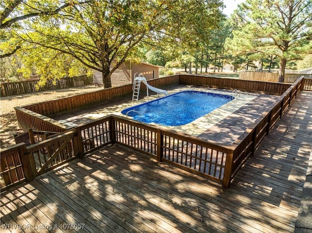 view of swimming pool with a wooden deck and a water slide