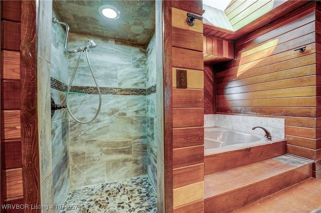 bathroom featuring a skylight, separate shower and tub, and wooden walls