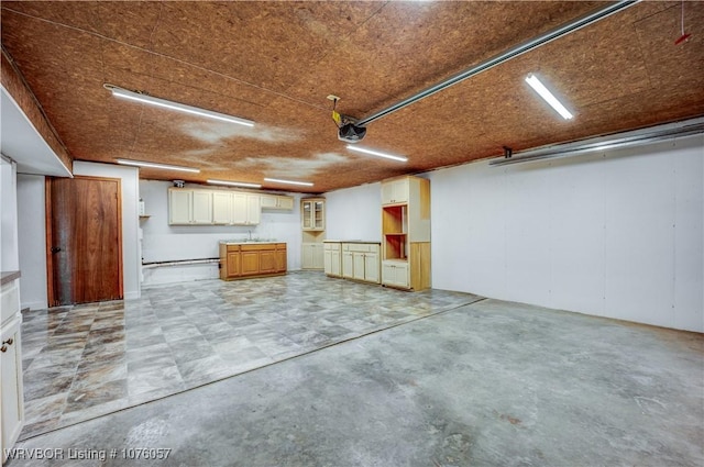 garage featuring a baseboard radiator, a garage door opener, and sink