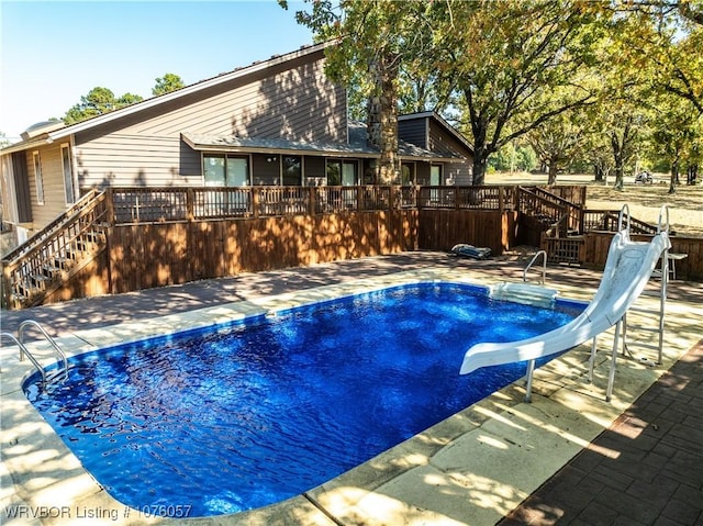 view of pool with a patio area, a deck, and a water slide