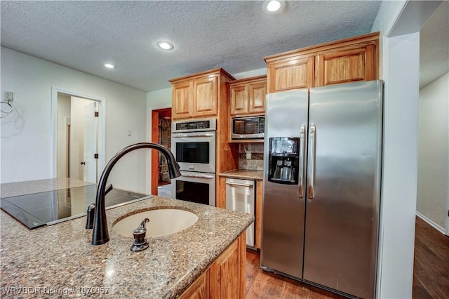 kitchen featuring a textured ceiling, light stone counters, light wood-type flooring, and stainless steel appliances