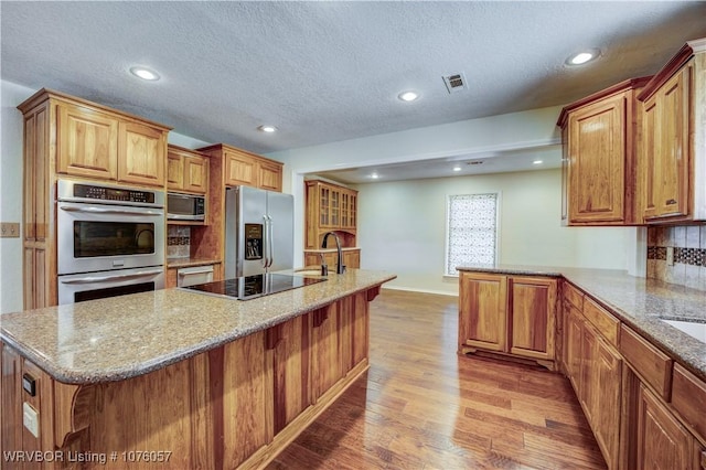 kitchen featuring backsplash, sink, light hardwood / wood-style floors, a kitchen bar, and stainless steel appliances