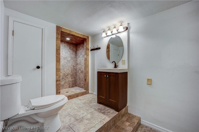 bathroom featuring vanity, toilet, a textured ceiling, and a tile shower