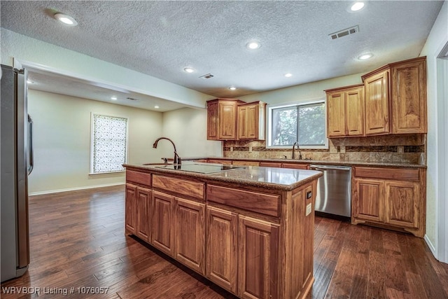 kitchen featuring a textured ceiling, tasteful backsplash, a kitchen island, dark hardwood / wood-style flooring, and stainless steel appliances