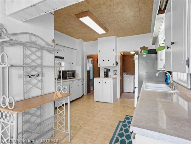 kitchen featuring white cabinets, washer / dryer, sink, and light parquet floors