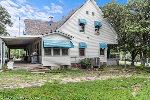 back of property with a yard and a carport