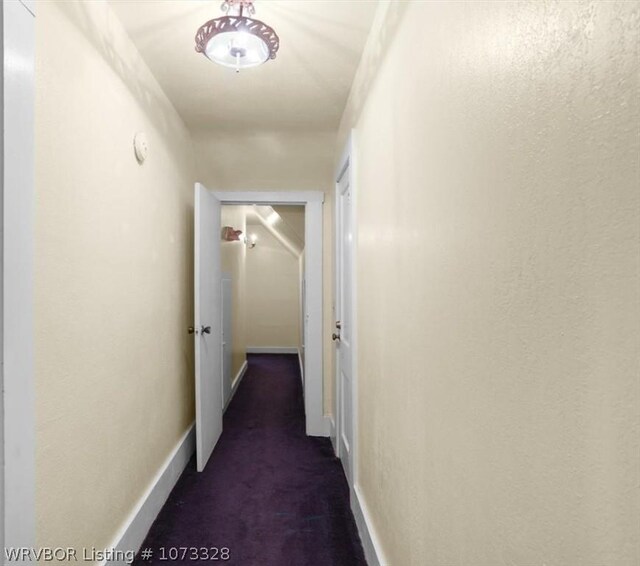 corridor featuring dark colored carpet