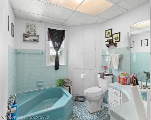 bathroom with vanity, tile patterned floors, toilet, tile walls, and a tub