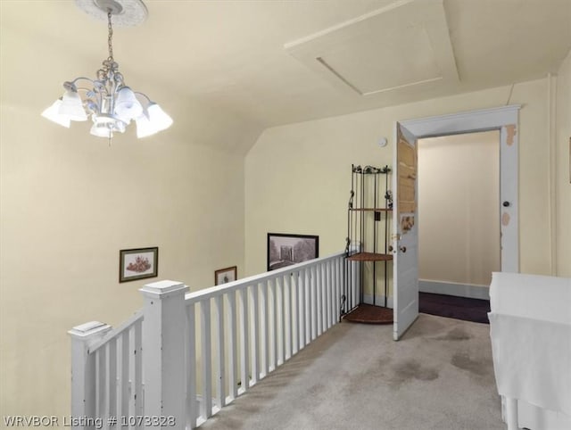 hall featuring vaulted ceiling, light carpet, and an inviting chandelier