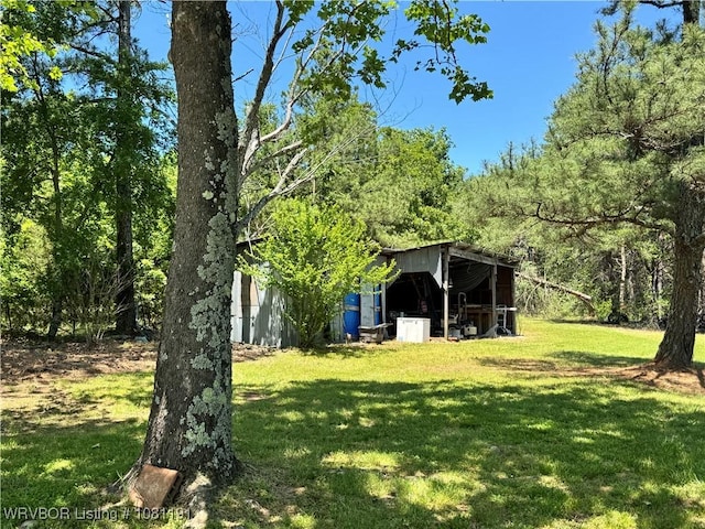 469497 975th Rd, Sallisaw, OK 74955 - view of grassy yard featuring an outdoor structure, an outbuilding, and a wooded view