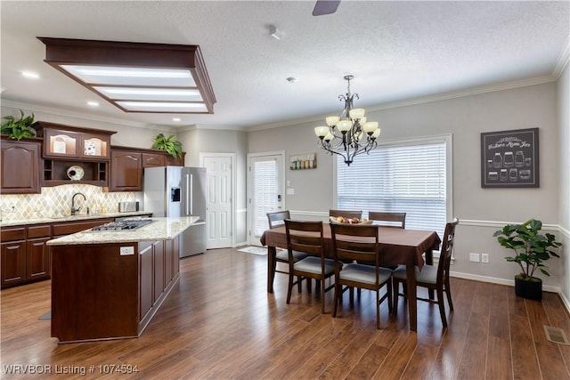 dining room with a chandelier, dark wood-style flooring, baseboards, a textured ceiling, and crown molding