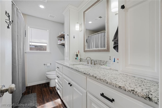 bathroom featuring vanity, toilet, wood finished floors, and visible vents